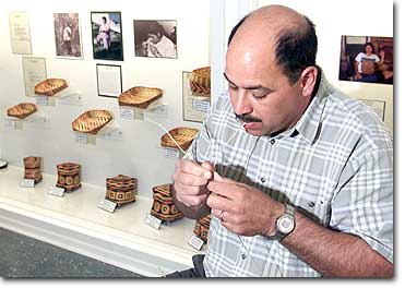 John Darden, museum interpreter and assistant curator at the Chitimacha Museum, peels away the husk of a piece of river cane in front of a display of traditional Indian baskets woven by some of his relatives. 