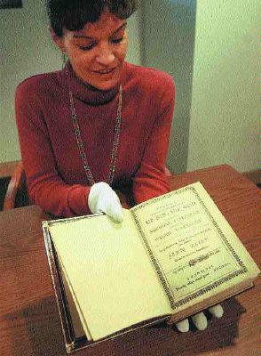 Charlene Jones, uses protective gloves to hold the 1685 Holy Bible translated into the Massachusett Indian language