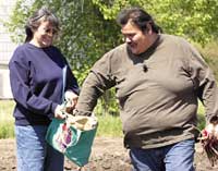 HoChunk spiritual leader Stuart Snake, right, takes a handful of prairie grass seeds from Cecelia Earth following a ceremony Tuesday blessing the site of the AiKiRuti healing gardens in Winnebago, Neb.