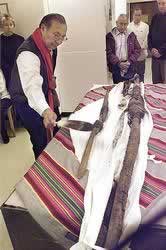 Doran Morris uses a cedar-smoked eagle feather to smudge Omahati, a sacred pole of the Omaha tribe.
