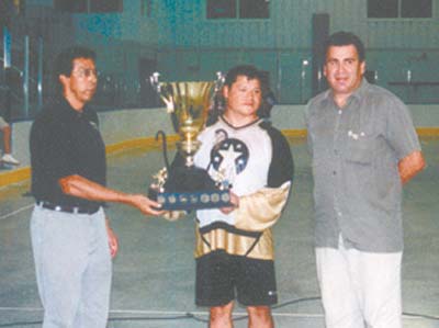 Tadadaho Sid Hill, Onondaga, left, presents the Iroquois Nations Cup to Cam Bomberry of Frog Pond Maulers I, a box lacrosse team from Six Nations Reserve, Ontario. Bob Tarbell, Onondaga, right, looks on. Photo by: Robert J. Taylor 