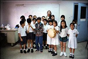 James Foguth, 11, center, wearing traditional Navajo attire, and his mother, Charlotte Kahn, back, poses with a class of Chinese students for whom they made cultural presentation. The two, on a trip sponsored by the Native American Ba'ha'i Institute, traveled to China in September to share the Navajo culture. 