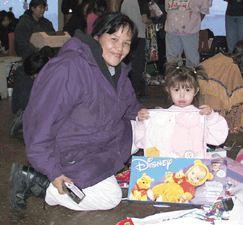 Arctic Village residents Julie Hollandsworth and her 3-year-old daughter Tia proudly display doll clothes Tia received from Santa. The 517th Airlift Squadron brought more than 5,000 pounds of food, supplies and gifts to the village. (Photo by 1st Lt. Johnny Rea)