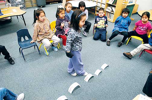 Kindergartners from the immersion school select the correct words on the floor for the items that teacher Angass'aq Sally Samson holds up during a vocabulary lesson. The school became a reality after Bethel parents lobbied the district for the program. 