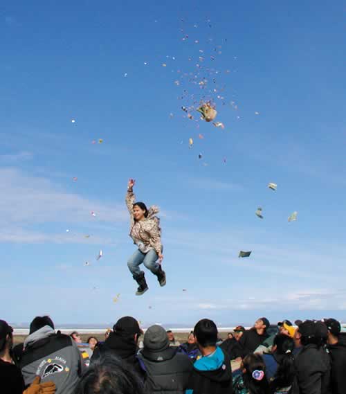 TOSSING GIFTS - The blanket toss is done by young mothers who gave birth to sons in the past year. As they get tossed up into the air, they throw candies, furs, blankets and material to a group of older ladies.
