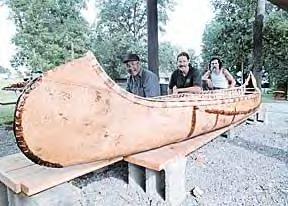 The finished canoe is proudly displayed by, left to right, Earl Mitchell, John Lindman and Tom Jackson.