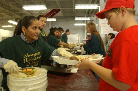 Sheila Esparza, left, of the Morongo Band of Mission Indians, dishes out part of a Thanksgiving dinner to an unidentified wildfire victim Monday, Nov. 3, 2003, at the Red Cross shelter in San Bernardino, Calif. The Morongo, who for more than a decade have donated 10,000 meals to Southern Californians annually at Thanksgiving, decided to bring the holiday early to approximately 1,000 wildfire victims still living at the shelter and who do not know if they will have a house to go home to.