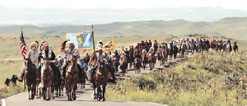 The Crow flag, at front right, whips in the breeze as tribe members ascend Last Stand Hill on their way to the dedication of the Indian Memorial at Little Bighorn Battlefield National Monument near Crow Agency last summer.