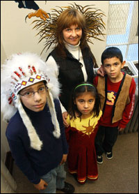 Students at the Wakina Sky Learning Center display the War Bonnet they created. Pictured from left are Brett Belgarde, Tisha Ball and Izain Belgarde. In the back is their teacher Pearle McGillis. - George Lane IR Staff Photographer