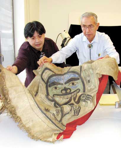 Jimmy (Kaw-Wei) George Jr. of Dei Shu Hit, the Raven Beaver clan of Angoon, helps Peter Jack of Teikweidi, Angoon's Bear clan, lay out a tunic that belonged to Kaa'kw' tlein, the house leader of the Bear House of Angoon and a grandfather of Jimmy George Jr., during their visit to a University of Pennsylvania museum in Philadelphia. The group dated the tunic to sometime in the early 1700s. The tunic belongs to the Bear Clan of Angoon. 