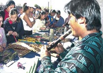Santiago Reyes (right) plays a flute as a group of kids looks over ones he made and was selling. Photo by Louie Villalobos 