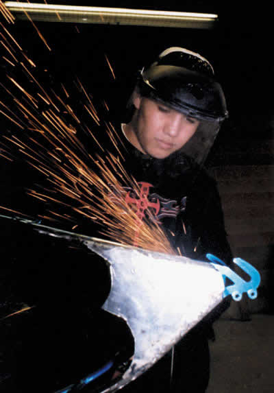Learning welding skills on a bicycle frame before moving up to automobiles, Kyle Coffman, 17, smooths out the metal with a buffer. Next year Pyramid Lake High School will have a larger self-contained automobile shop where the students will have the tools and the space to be taught basic car repairs and maintenance. (Photo by Matt Ross)