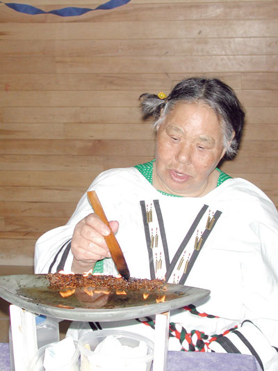 Elder Louisa Ippak expertly tends the qulliq as her daughter, Mina, prepares to graduate from the Nunavut Teachers Education Program.