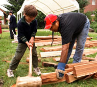 Odell Jones, 6, gets help from Deitrich Peters, a Grand Ronde tribal member, lining up a yew wedge to split a long plank from a cedar log at a demonstration at the UO Museum of Natural History on Saturday afternoon. Photo: Wayne Eastburn / The Register-Guard